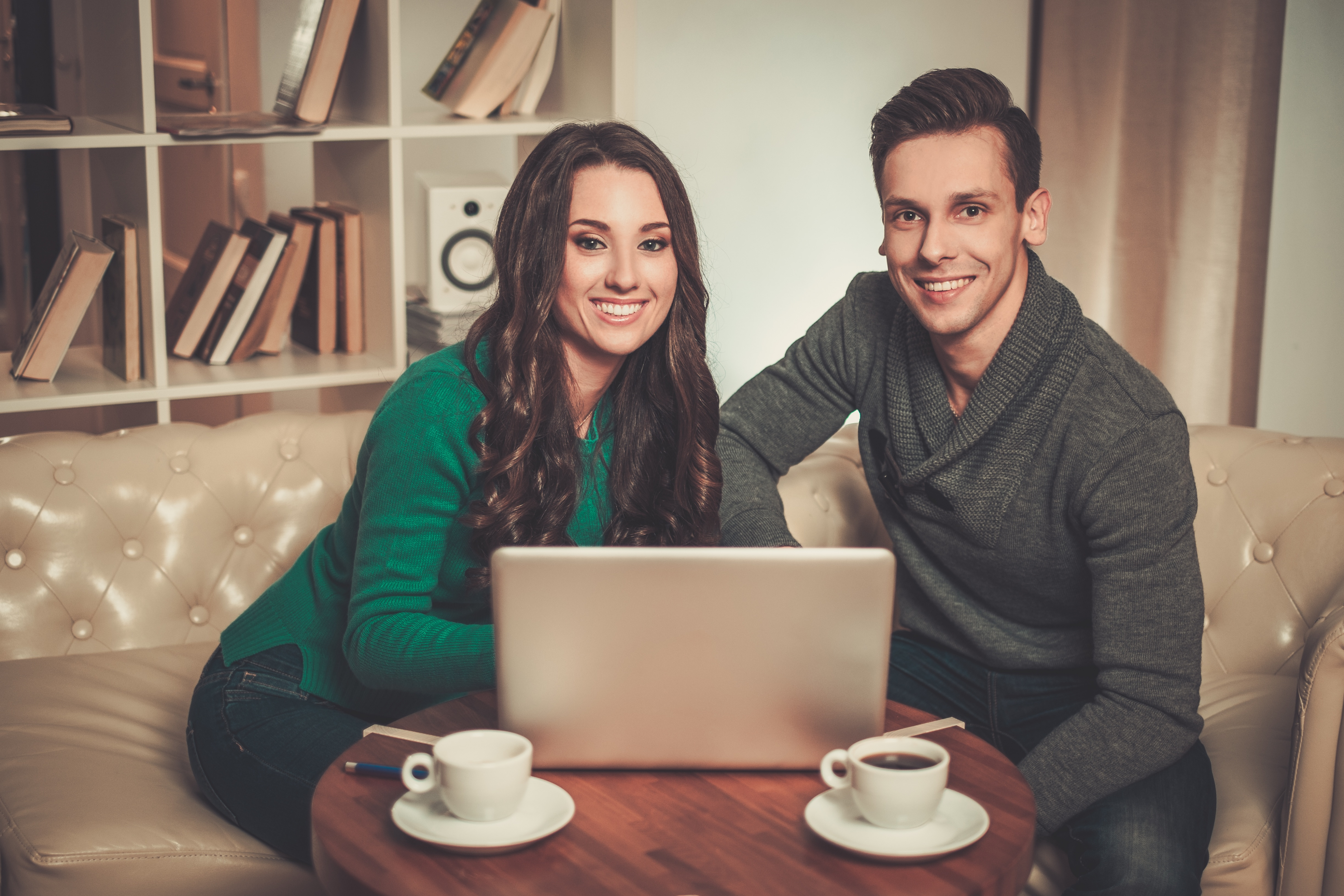 A couple sitting together at home in front of a laptop